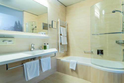 a bathroom with a sink and a shower and a tub at Hotel Tyrol am Haldensee in Haldensee