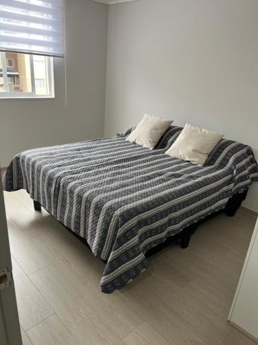 a large bed with a black and white blanket at Departamento en Villarrica con Piscina y Estacionamiento Privado in Villarrica