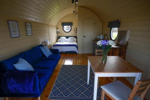 a living room with a blue couch and a bed at Spring Tide Cliff Top Glamping Pod with direct Sea Views in Birchington