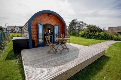 a tiny house with a table and chairs on a deck at Spring Tide Cliff Top Glamping Pod with direct Sea Views in Birchington