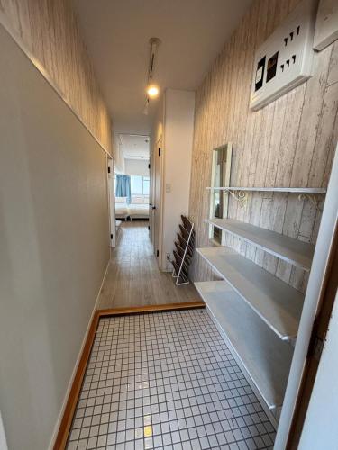 a hallway with a tile floor and shelves at HOTTOSTAYman401 in Sasashimachō