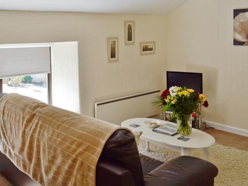 a living room with a couch and a table with flowers at Rosecraddoc Manor - Hayloft in Saint Cleer
