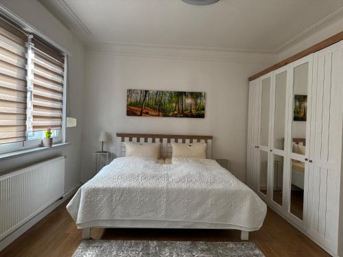 a white bedroom with a bed and a window at Ferienwohnung Chiara in Mettlach