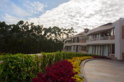 a building with bushes and flowers in front of it at Hotel Medina Del Lago in Otavalo