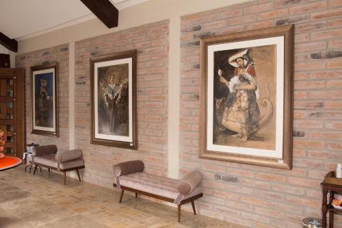 a room with a brick wall with paintings on it at Hotel Medina Del Lago in Otavalo