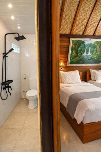a bedroom with a bed and a bathroom with a toilet at Putra Bali Villa by Antara in Klungkung