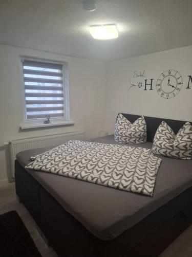 a bed in a bedroom with a clock on the wall at Ferienwohnung Alte Glaserei in Ilsenburg