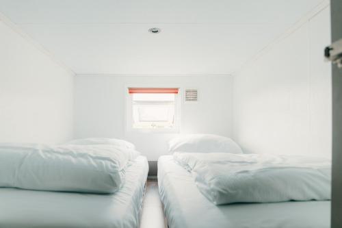 two beds in a white room with a window at Recreatiepark De Boshoek in Voorthuizen
