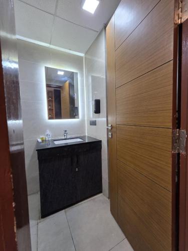 a bathroom with a sink and a mirror and a wooden door at Omex hazratganj arjunganj in Nalmatha