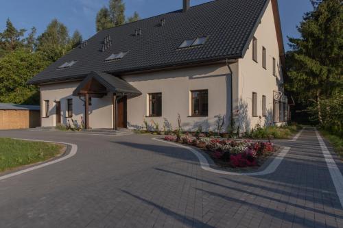 a white house with a black roof and a driveway at Gościniec Szpakówka in Czeremcha