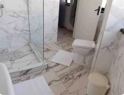 a bathroom with a toilet and a glass shower at Grand et chic appartement in Dakar