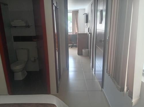 a hallway of a bathroom with a toilet and a sink at Hotel Cafe y Miel in Pasto