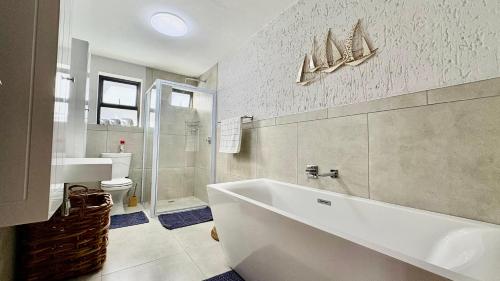 a bathroom with a tub and a sink and a toilet at Sea La Mer Villa in Wilderness