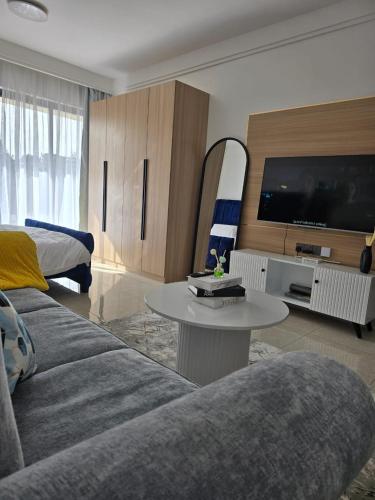 a living room with a couch and a table and a tv at Serene Studio near UN headquarters and Gigiri in Ruaka