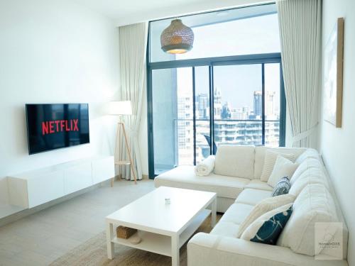 a living room with a white couch and a tv at Elegant Haven by Meraki - New 1 Bed Garden View in Dubai