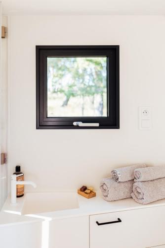 a white bathroom with a window above a sink at Glamping Silverboy in Toužim