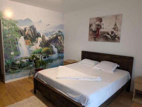 a bedroom with a bed with a painting on the wall at Waterfall Studio in Bucharest