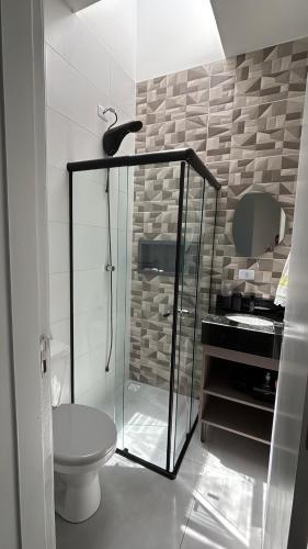 a bathroom with a glass shower and a toilet at Beach house in Matinhos in Matinhos