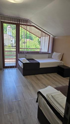 ein Schlafzimmer mit zwei Betten und einem großen Fenster in der Unterkunft Къща Амфора in Trjawna