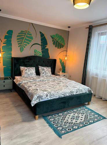 a bedroom with a bed with green leaves on the wall at Best Apartment Scheia in Suceava