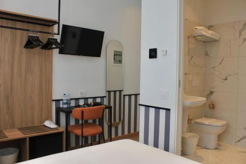 a bathroom with a toilet and a tv on the wall at HÕMA Certosa District in Milan