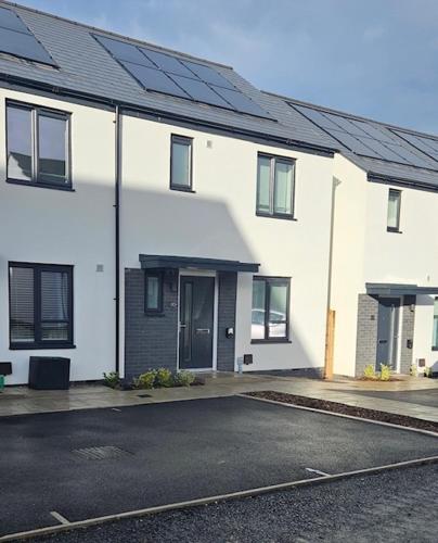 a white house with solar panels on top of it at Eco House by Science Park, Airport and City Centre in Exeter