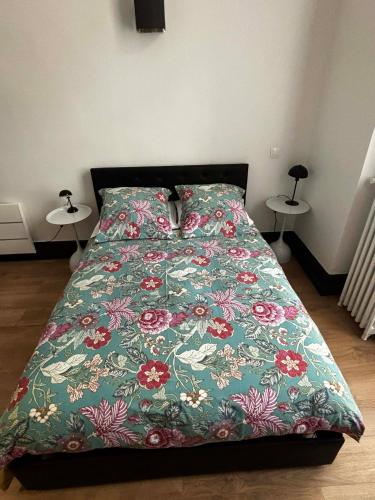 un letto con un piumone verde con dei fiori sopra di Les Cariatides a Lille