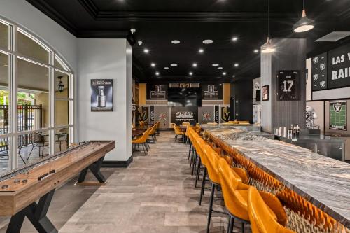 a restaurant with a long bar with yellow chairs at Club Wyndham Grand Desert in Las Vegas