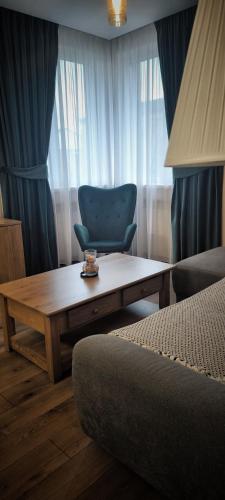 a room with a table and a blue chair and a couch at Apartamentul Cetății Alba Iulia in Alba Iulia