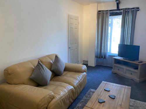 a living room with a couch and a television at Rosecraddoc Manor - Coachman's in Saint Cleer