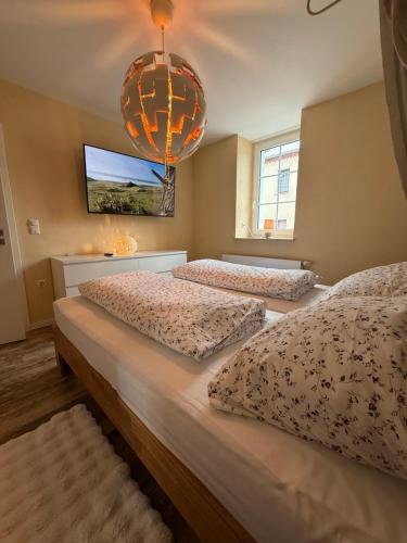 two beds in a bedroom with a chandelier at Ferienwohnung Könitz, Ilschen in Naumburg