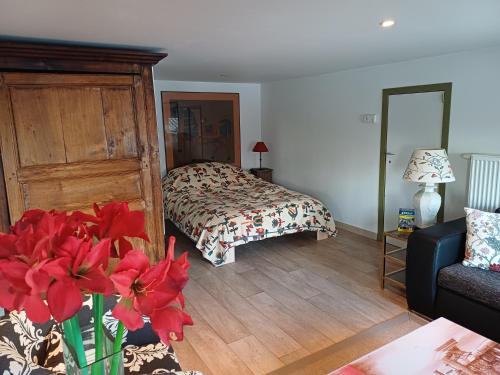 a bedroom with a bed and a vase with red flowers at Lozerhof Studio in Kruisem