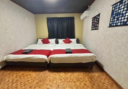 a bedroom with a large bed with red pillows at HOTTOSTAYKiyosu in Nagoya