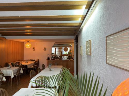 a restaurant with white tables and chairs and a counter at Hotel Garni Sebastian in Kirrweiler