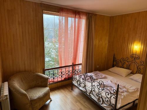 a bedroom with a bed and a chair and a window at Hotel palas tatariv in Tatariv