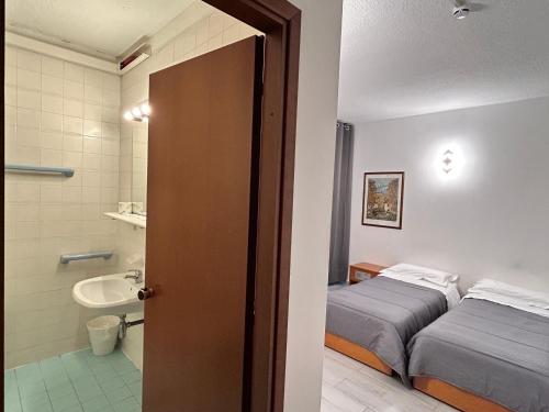 a hotel room with two beds and a bathroom at La Fenice Hotel in Reggello