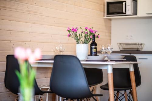 a table with chairs and a bottle of wine and flowers at Wrzosowy Zakątek Sarbinowo in Sarbinowo