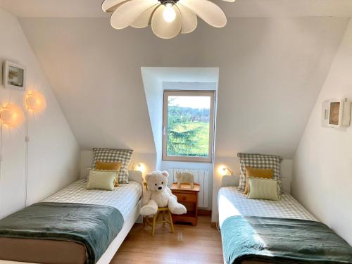 two beds in a room with a teddy bear between them at Double J - Omaha beach in Formigny