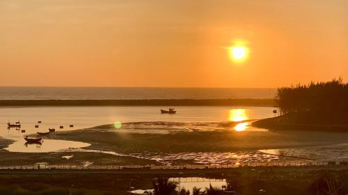 a sunset over a body of water with boats in it at ML Homestay in Binh Chau