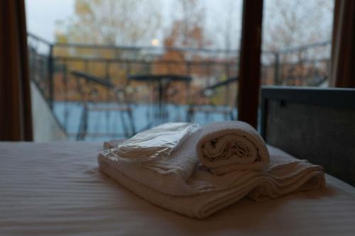 a towel sitting on top of a bed with a window at Hotel Nicolo in Tbilisi City