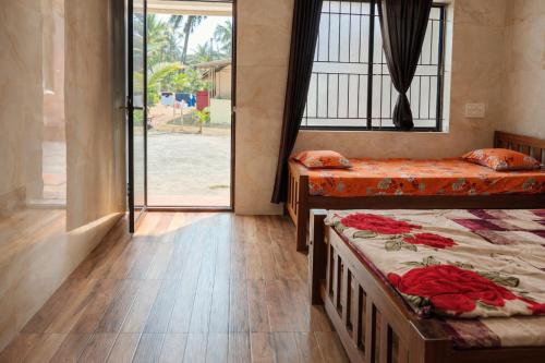a room with two beds and a large window at Manan Beach Resort in Malpe