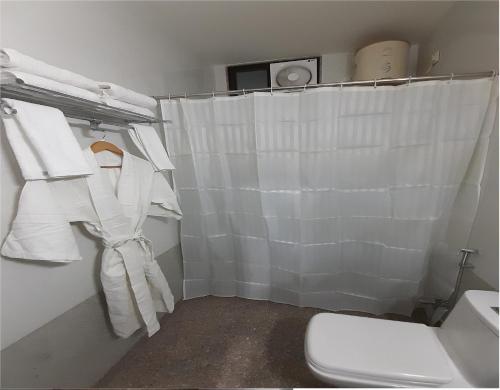 a bathroom with a white shower curtain and a toilet at Hotel Aravali Hills View in Kuchāman City