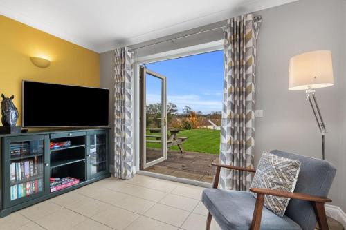 a living room with a tv and a sliding glass door at Llais Y Mor - large holiday home close to the beach - sleeps 8 in Carmarthen