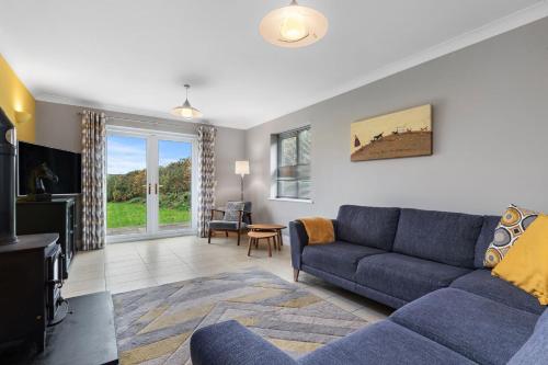 a living room with a blue couch and a tv at Llais Y Mor - large holiday home close to the beach - sleeps 8 in Carmarthen