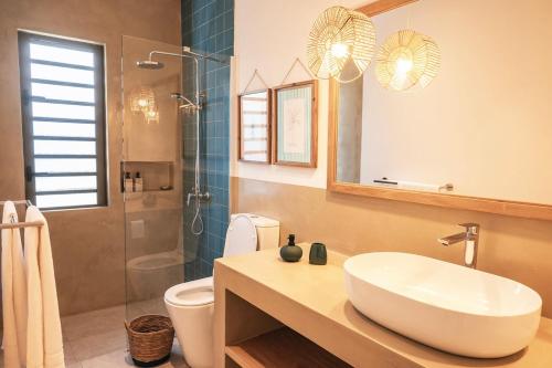 a bathroom with a sink and a toilet and a shower at La Pépite Villa in Pointe d'Esny