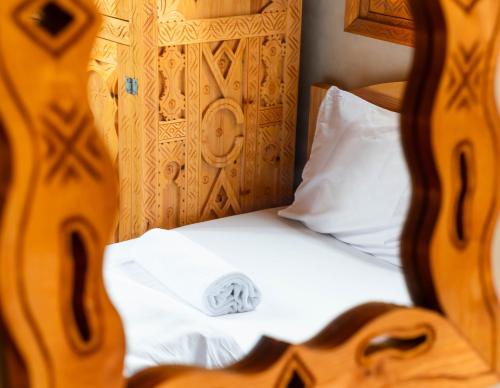 a close up of a bed with white sheets and a pillow at Berber Surf House in Tamraght Ouzdar