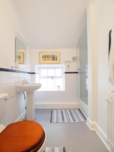 a bathroom with a toilet and a sink and a window at Carpenter's Cottage in Matlock