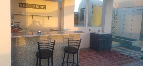 Una cocina con dos taburetes de bar y una encimera con fregadero. en Sunny sky, en Quseir