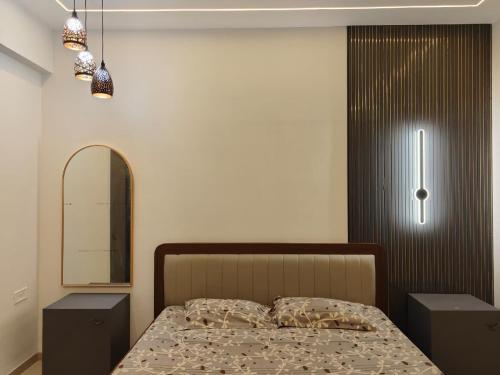 a bedroom with a bed with two night stands and a mirror at Staeg Meadow View 3BHK - 501 in Indore