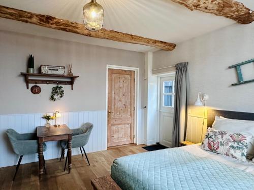 a bedroom with a bed and a desk and a table at B&B de Perenboom in Eck en Wiel